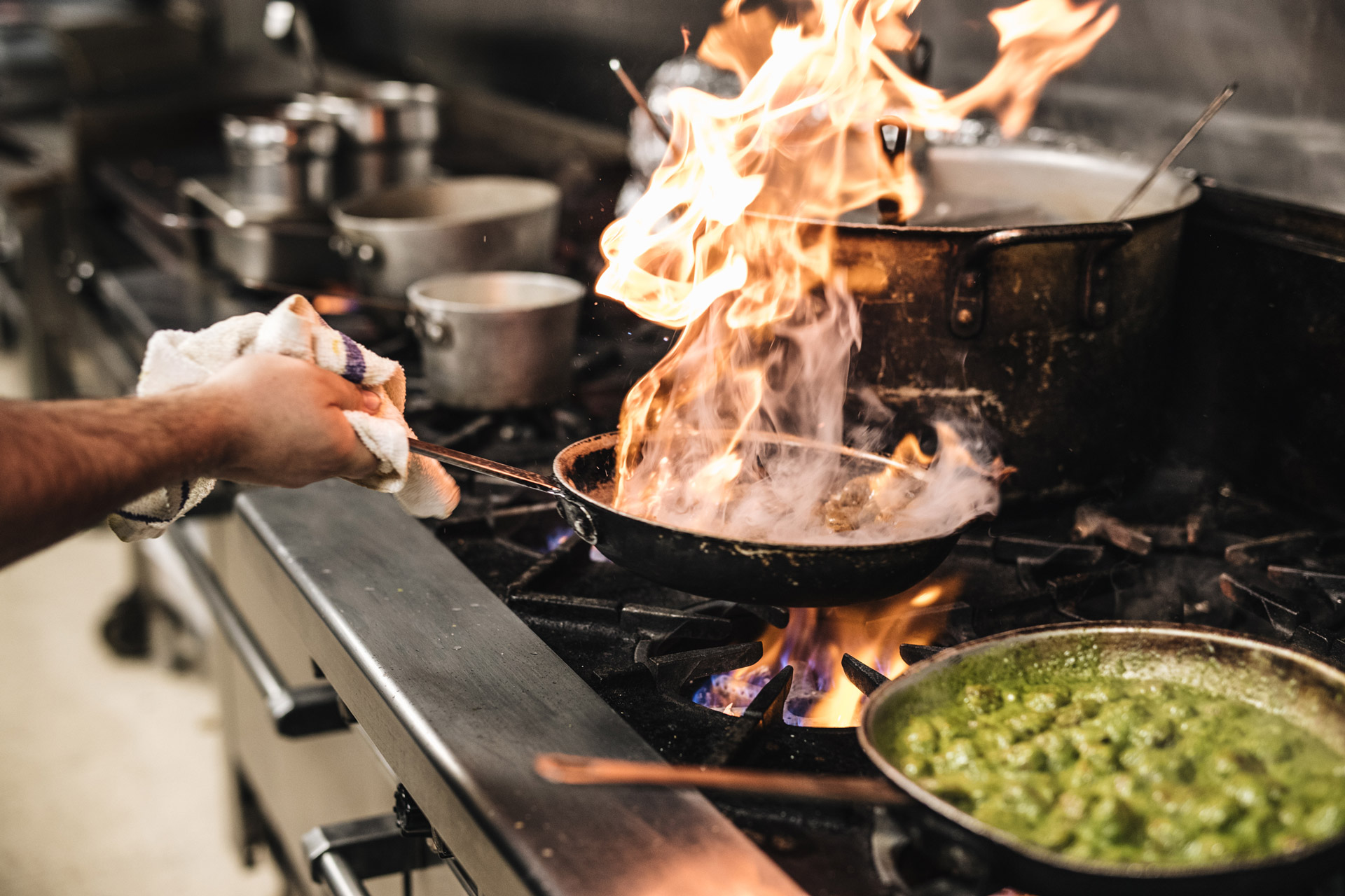 Hand shaking a skillet over an oven